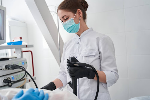 A healthcare professional wearing a surgical mask and gloves is operating a medical device during a procedure